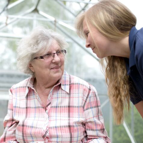 Hüttenhospital - Eine Seniorin schaut lächelnd eine Pflegerin an